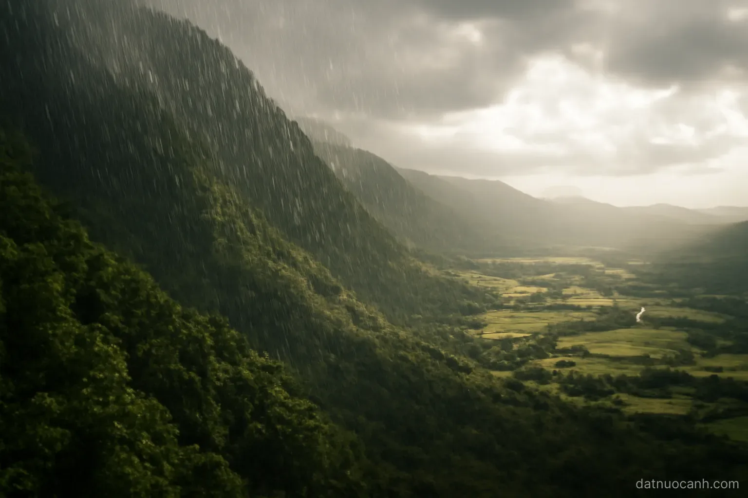 Rain falling on the windward side of green mountains while the far valley stays sunlit, no text